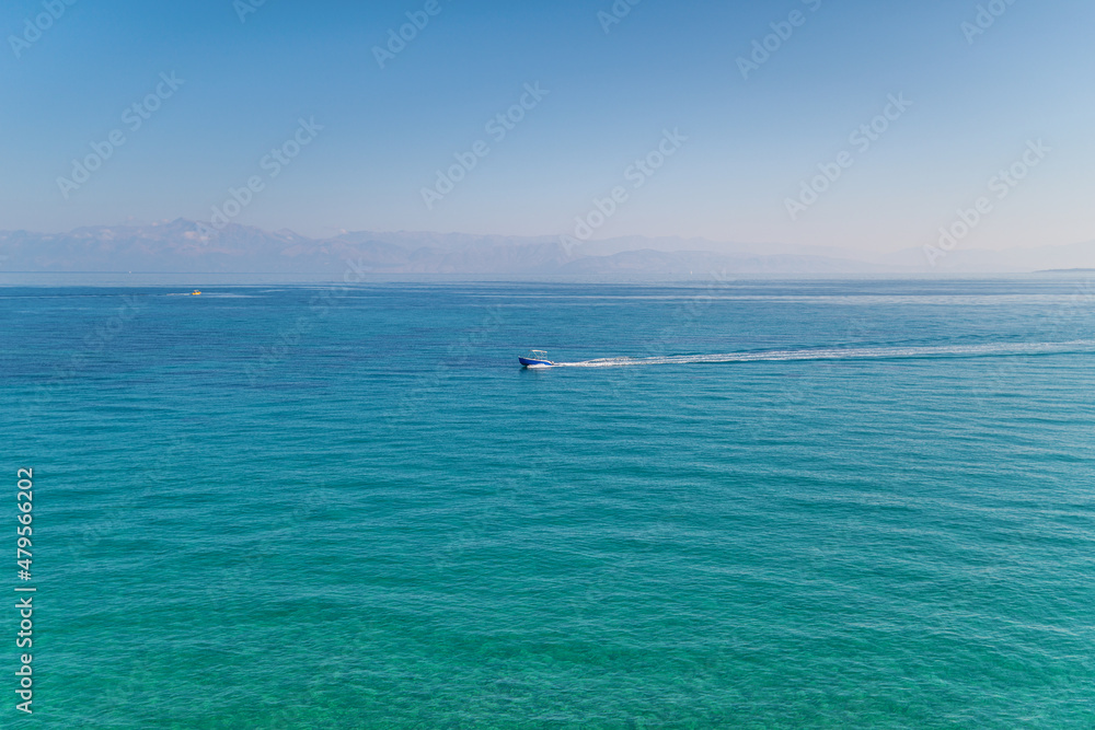 Motorboat sailing on sea against horizon under blue sky