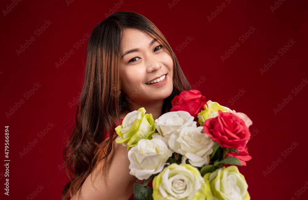 Beautiful young Asian woman smiling with a bouquet of red roses on red background. Beautiful young Asian woman smiling with a bouquet of red roses on red background.