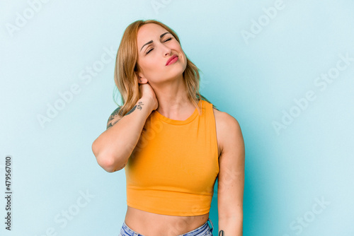 Young caucasian woman isolated on blue background having a neck pain due to stress, massaging and touching it with hand.