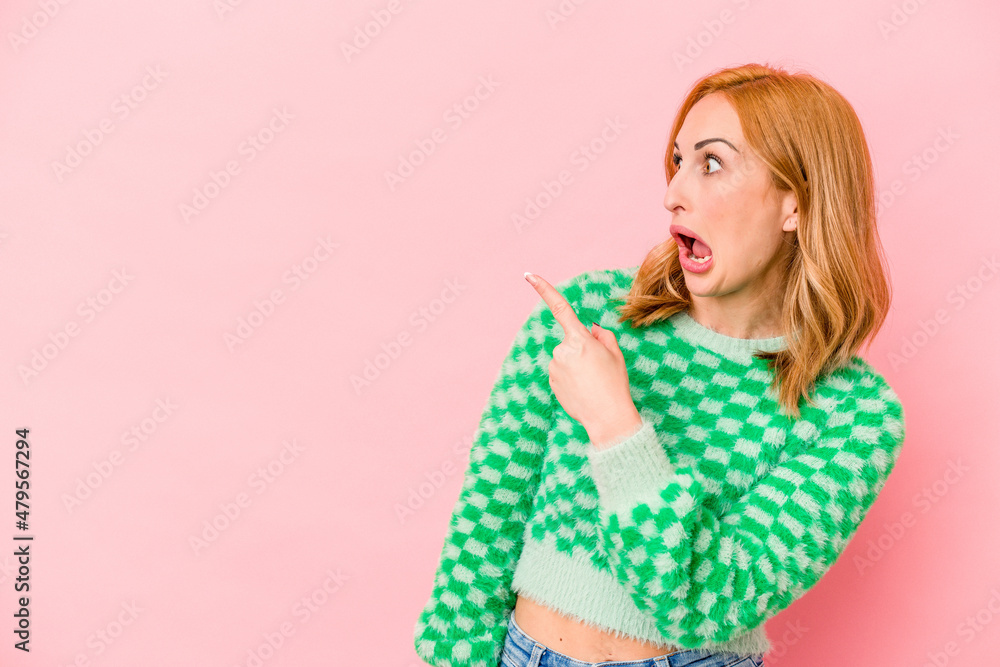 Young caucasian woman isolated on pink background points with thumb finger away, laughing and carefree. Young caucasian woman isolated on pink background points with thumb finger away, laughing and carefree.