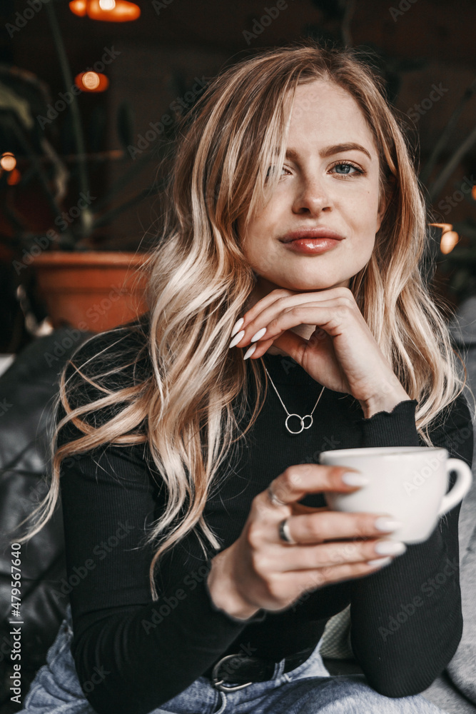 Close up portrait of a woman in cafe. She is holding a cup of coffee. Close up portrait of a woman in cafe. She is holding a cup of coffee.