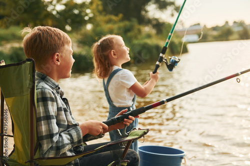 Medium sized lake. Boy with his sister in on fishion outdoors at summertime together