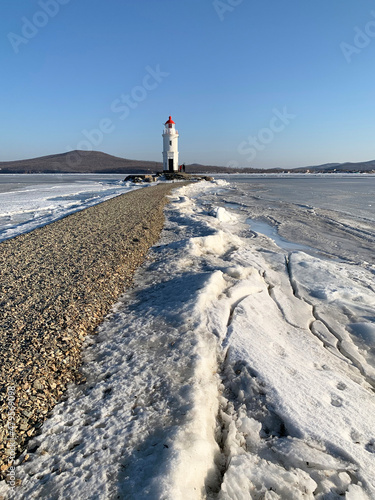 Vladivostok. Egersheld Lighthouse (1876) on the tip of the Shkota peninsula-Tokarevskaya koshka in winter on a sunny day photo