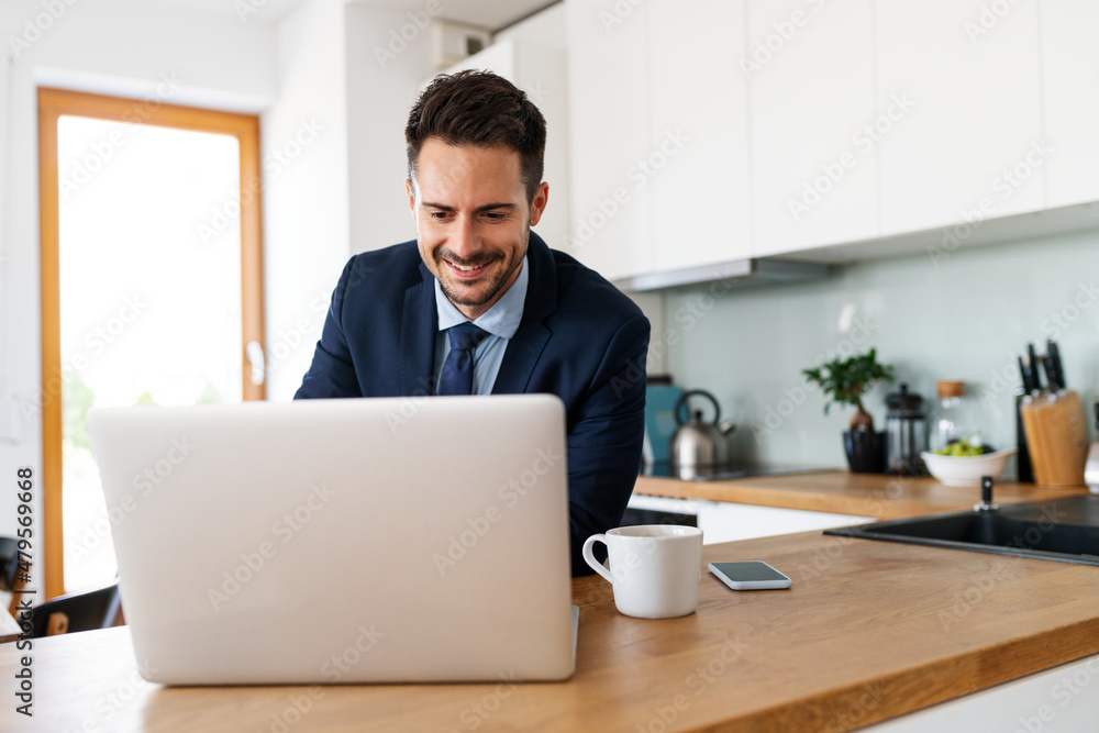 Handsome businessman using laptop in the kitchen Handsome businessman using laptop in the kitchen