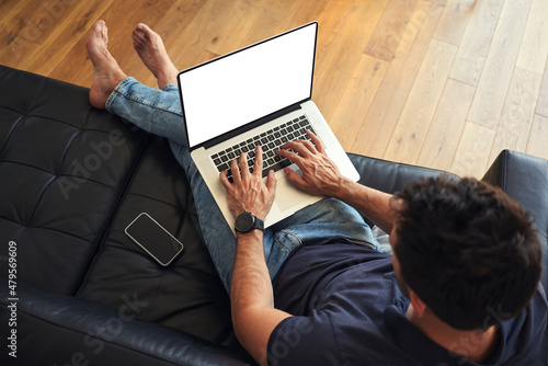 Fotografija Man using laptop sitting on sofa with visible screen