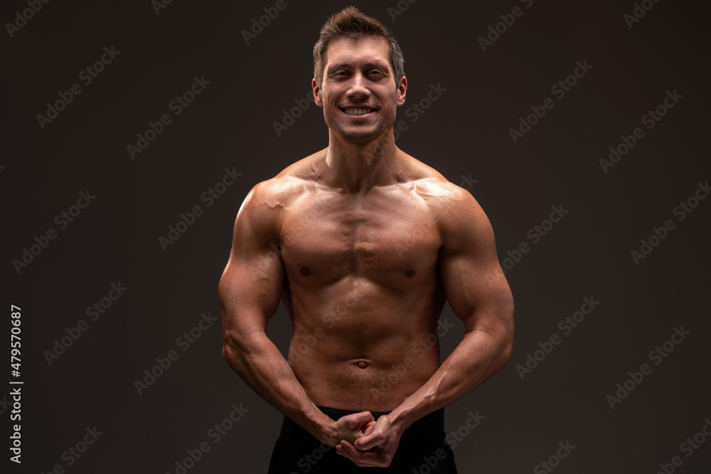 Young athletic man with naked torso looking at the camera isolated on a black background. Bodybuilding and strong people concept Young athletic man with naked torso looking at the camera isolated on a black background. Bodybuilding and strong people concept