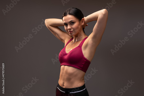 Fototapeta Naklejka Na Ścianę i Meble -  Waist up portrait view of excited slim young woman in sportswear posing and smiling to the camera isolated over brown studio background. Sport and healthy lifestyle
