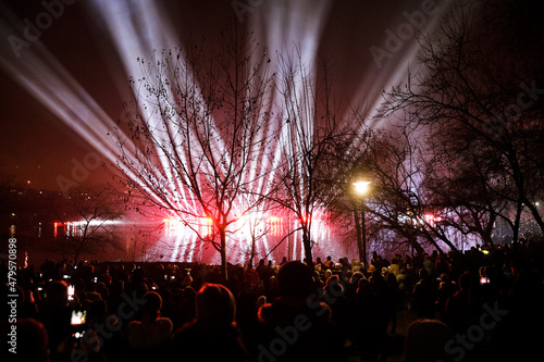 People watch and film a laser show over the lake during New Years celebrations in the Alexandru Ioan Cuza park in Bucharest.
