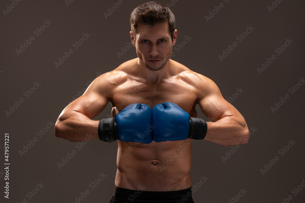 Boxing stance. Muscular caucasian sports man in gloves looking at camera over the brown studio background. Stock photo Boxing stance. Muscular caucasian sports man in gloves looking at camera over the brown studio background. Stock photo