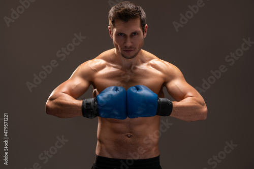 Boxing stance. Muscular caucasian sports man in gloves looking at camera over the brown studio background. Stock photo