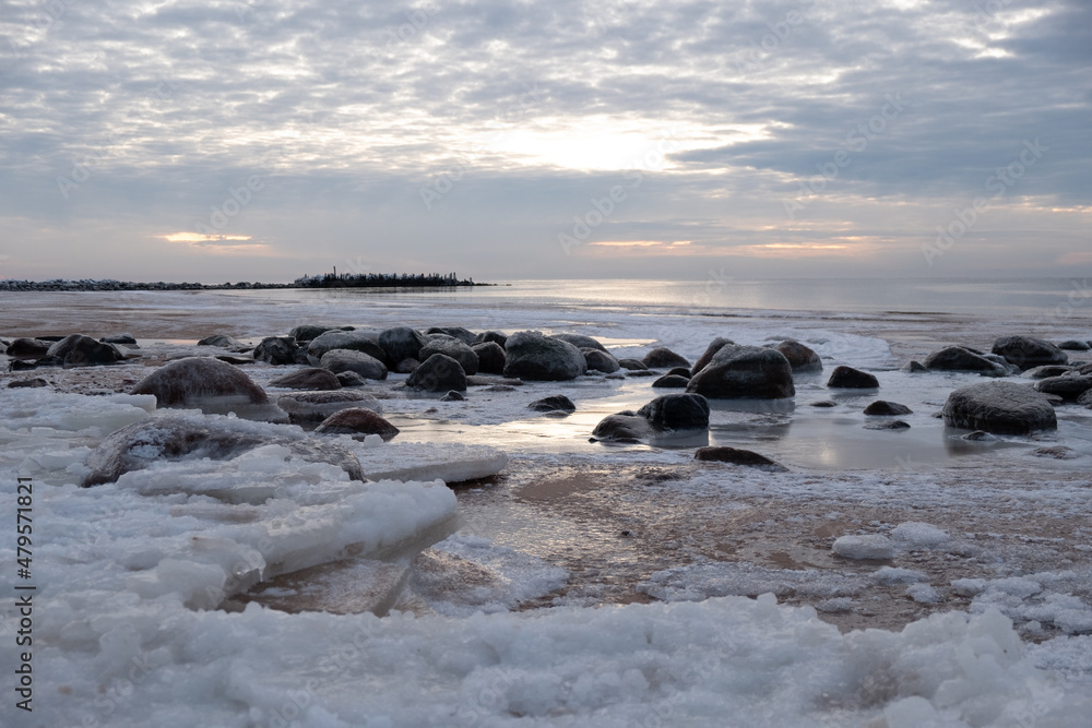 Ice blocks at the beach in winter evening by the sea with rocks
