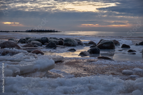 Fototapeta Naklejka Na Ścianę i Meble -  Ice blocks at the beach in winter evening by the sea with rocks