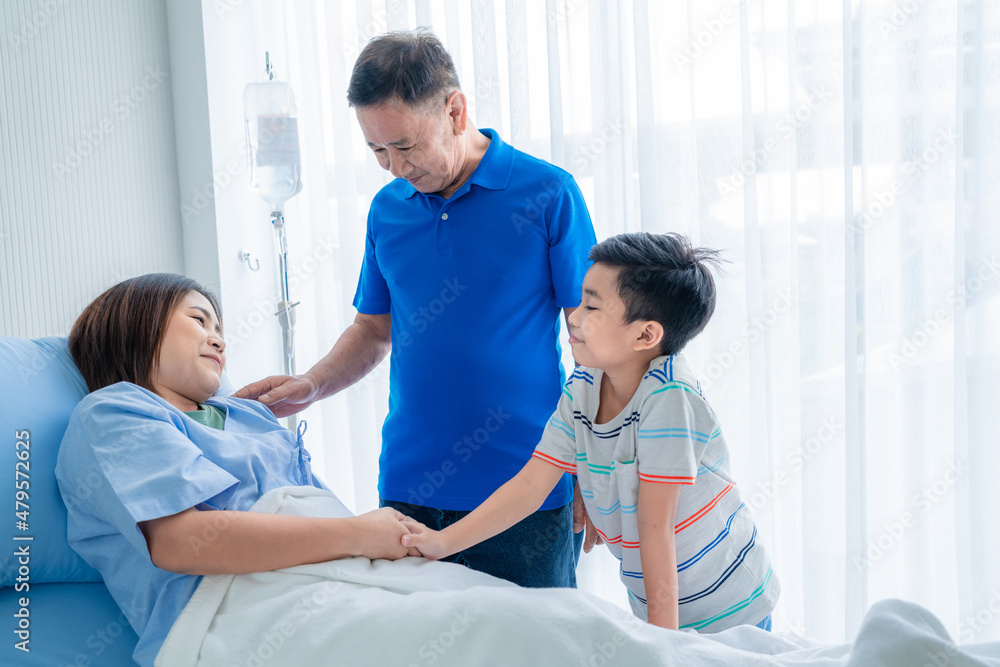 Obraz premium Asian woman, sick, stay in hospital. lying on the patient's bed beside the window A son and family came to visit and support.