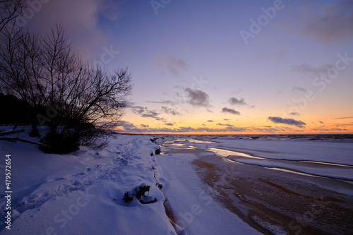 sunset in winter small river frozen snow in the beach