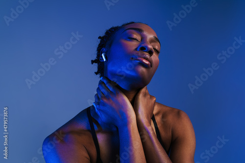 Black young sportswoman in earphones looking at camera