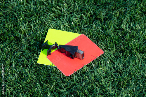 Referee soccer, football game whistle, red and yellow cards on green grass. Two penalty cards and a whistle for the referee F