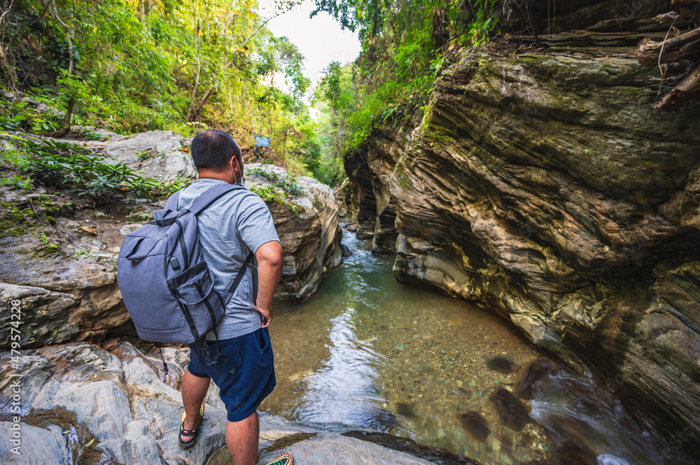Back of Asian backpacker with Landscape view of Wang Sila Lang canyon at pua District nan.Nan is a rural province in northern Thailand bordering Laos Back of Asian backpacker with Landscape view of Wang Sila Lang canyon at pua District nan.Nan is a rural province in northern Thailand bordering Laos
