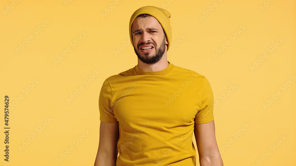 upset man in beanie hat isolated on yellow upset man in beanie hat isolated on yellow