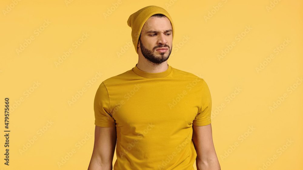 displeased man in beanie hat smelling isolated on yellow displeased man in beanie hat smelling isolated on yellow