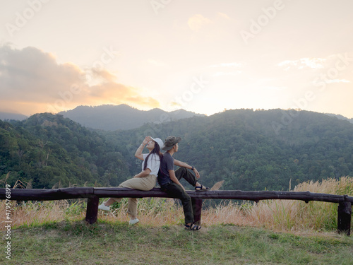 Happy young couple watching the sunset in the mountains at Mae Wong National Park, Kamphaeng Phet, Thailand © TongTa