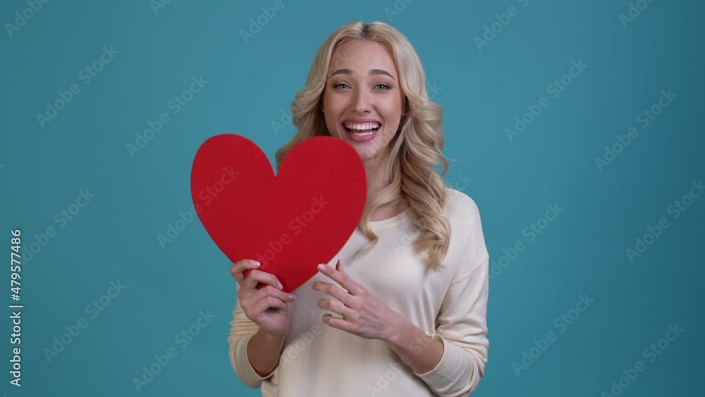 Attractive lady hold postcard heart fist up isolated blue color background Attractive lady hold postcard heart fist up isolated blue color background