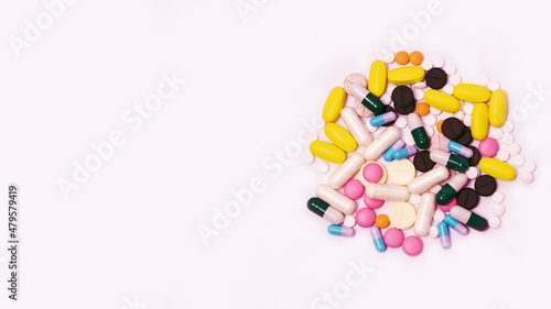 Variety of medicines and capsules in a woman's palm on a blue background. The concept of consuming a large number of drugs