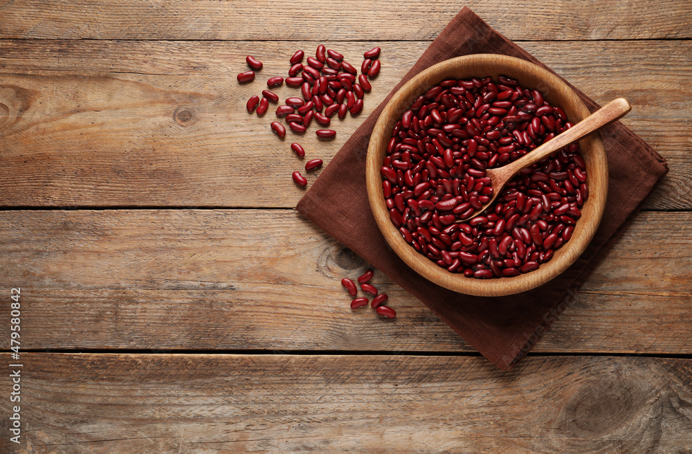 Raw red kidney beans with bowl, spoon and napkin on wooden table, flat lay. Space for text Raw red kidney beans with bowl, spoon and napkin on wooden table, flat lay. Space for text
