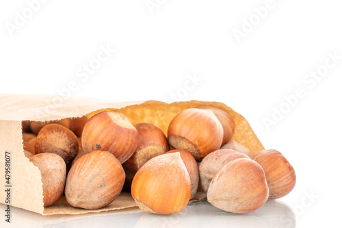 Several organic hazelnuts in a paper bag, close-up, isolated on white.
