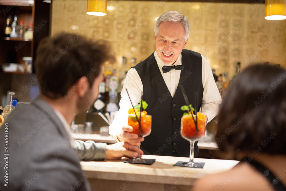 Bartender serving cocktails to a young couple Bartender serving cocktails to a young couple