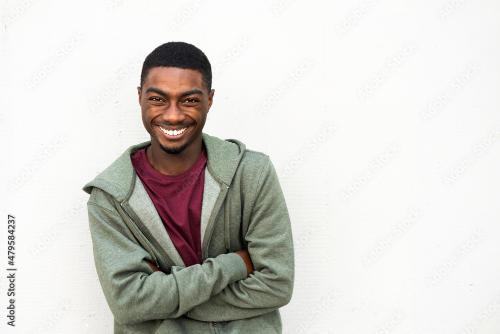 smiling young African American man with arms crossed by white background smiling young African American man with arms crossed by white background