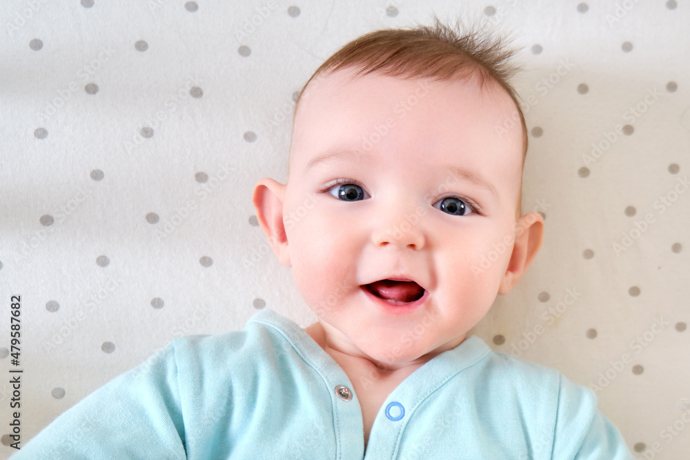 Teeth are teething at the infant baby, smiling face close-up. Portrait of a happy child aged six months