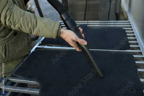 Man cleaning auto carpets with vacuum cleaner at self-service car wash, closeup