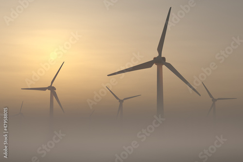 Wind turbines rise from thick fog