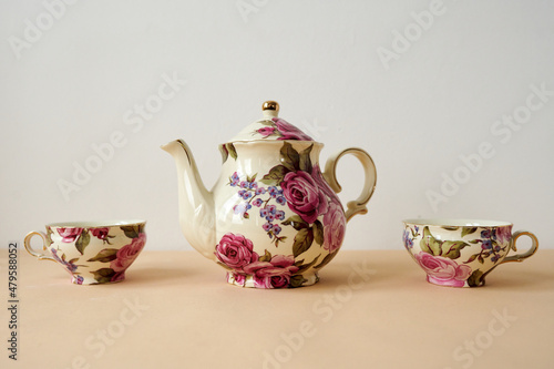 vintage teapot and cups on white and peachy background