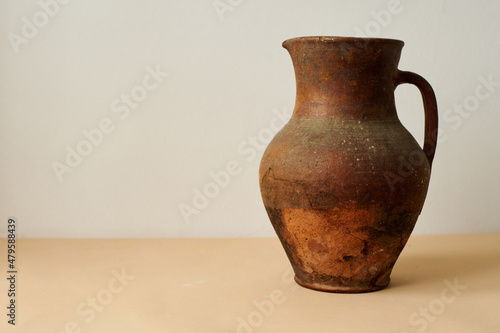 old ancient brown jug on white and  peachy background photo