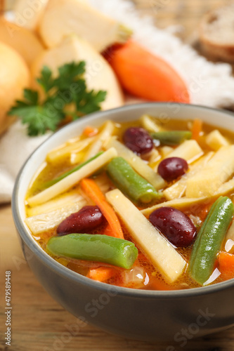 Bowl of delicious turnip soup on wooden table, closeup