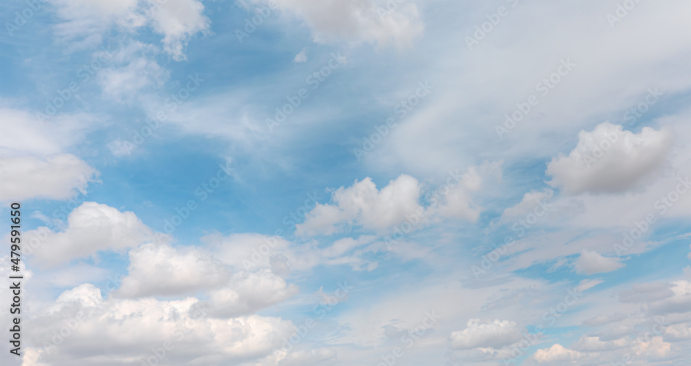 Blue sky and white clouds background - Pillowy clouds cover a blue sky in the background Blue sky and white clouds background - Pillowy clouds cover a blue sky in the background