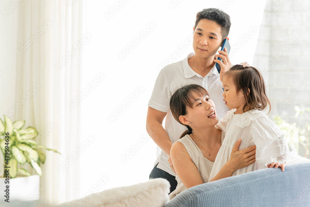 Familia asiática sentados con su hija mientras su padre hace una llamada por teléfono móvil al doctor