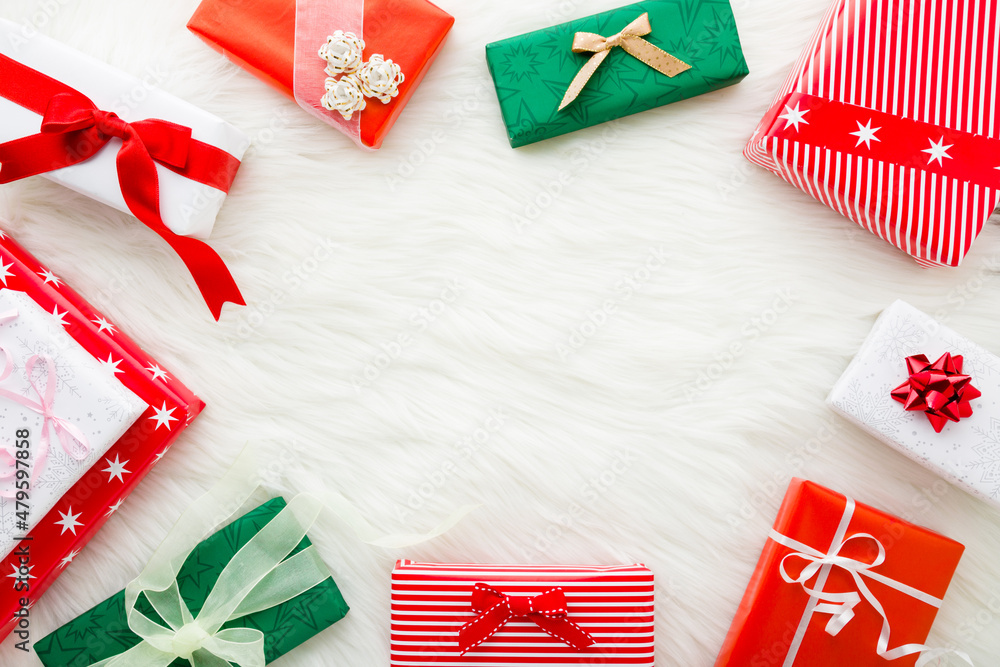 Colorful wrapped present boxes on white soft fluffy fur blanket background. Gifts time on Christmas or New Year. Closeup. Empty place for wishes text quote or sayings. Top down view. Colorful wrapped present boxes on white soft fluffy fur blanket background. Gifts time on Christmas or New Year. Closeup. Empty place for wishes text quote or sayings. Top down view.
