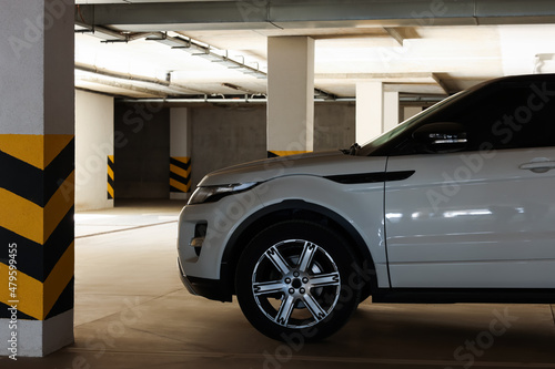 White car near column with warning stripes in parking garage