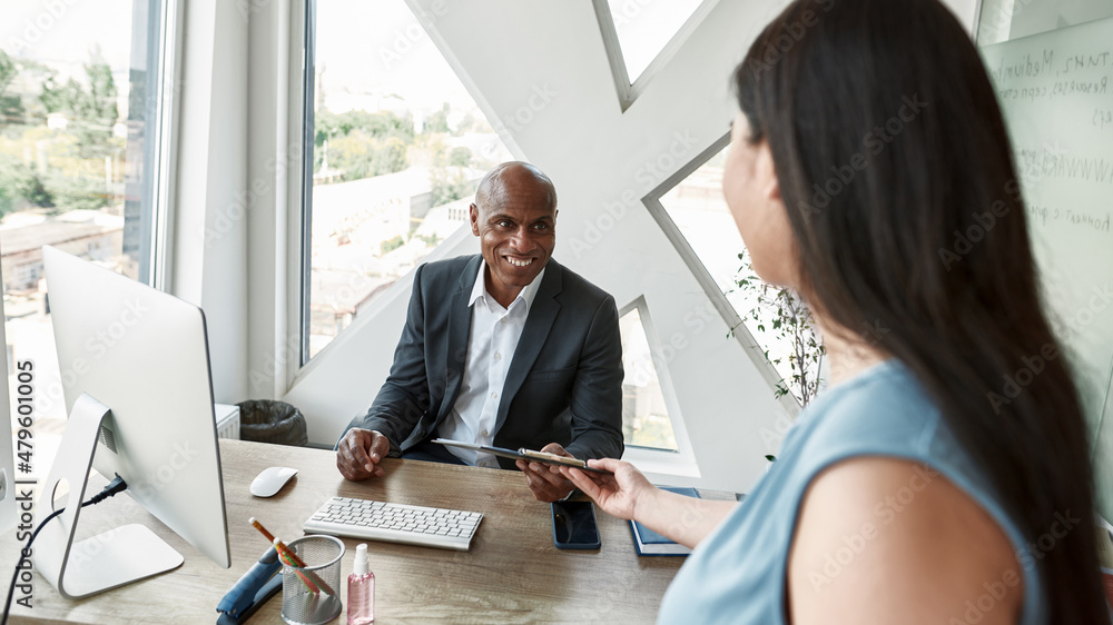 Smiling black male boss take report from employee