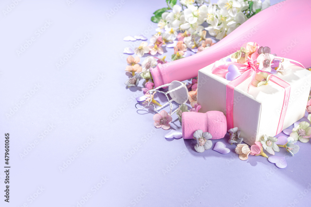 Cute high-colored Valentine day background, with pink colored champagne bottle, spring blossom flowers, little heart decor, on violet very peri color background flatlay copy space Cute high-colored Valentine day background, with pink colored champagne bottle, spring blossom flowers, little heart decor, on violet very peri color background flatlay copy space