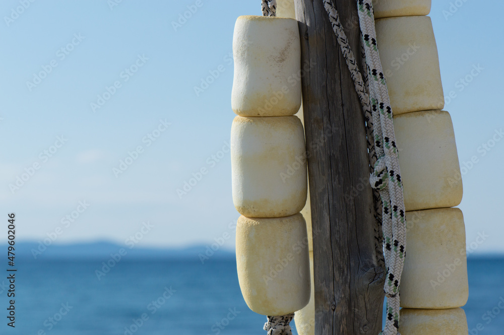 Old authentic maritime ropes and buoys hanging on a wooden stick by the sea, nautical background Old authentic maritime ropes and buoys hanging on a wooden stick by the sea, nautical background