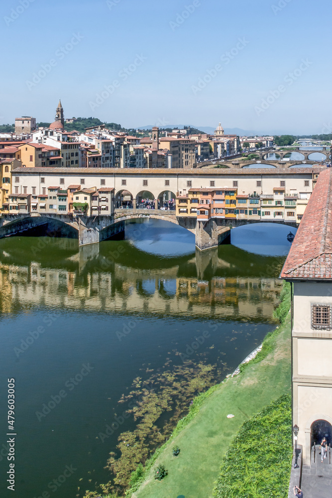 The Ponte Vecchio bridge over the Arno River on a sunny day in Florence, Italy.
