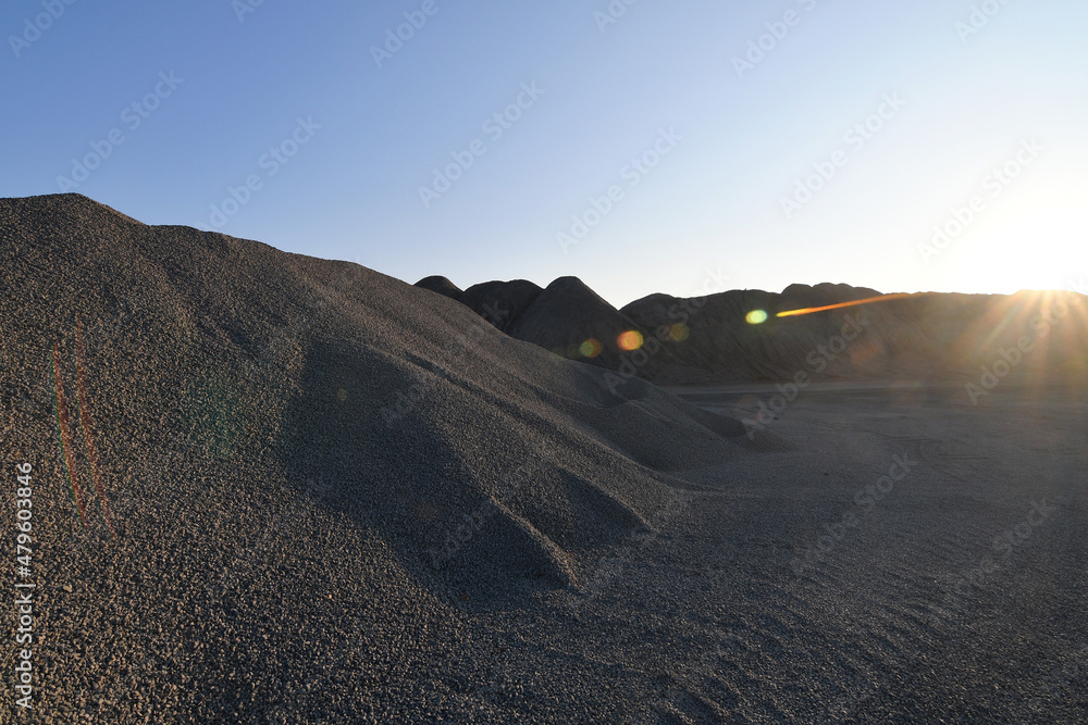 Big piles of gravel in a granite quarry at sunset with sunflare, industrial background Big piles of gravel in a granite quarry at sunset with sunflare, industrial background