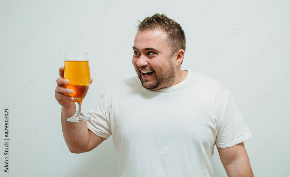 Positive bearded fat guy with a big glass of beer and smiling. Funny young man feeling happy and relaxed, with cold fresh beer in his hands after a hard day at work Positive bearded fat guy with a big glass of beer and smiling. Funny young man feeling happy and relaxed, with cold fresh beer in his hands after a hard day at work