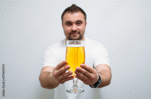 Positive bearded fat guy with a big glass of beer and smiling. Funny young man feeling happy and relaxed, with cold fresh beer in his hands after a hard day at work