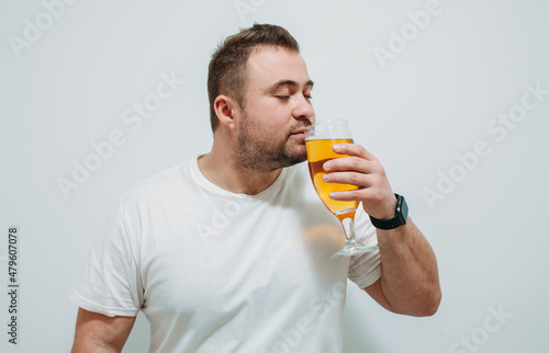 Positive bearded fat guy with a big glass of beer and smiling. Funny young man feeling happy and relaxed, with cold fresh beer in his hands after a hard day at work