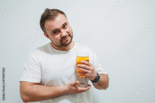 Positive bearded fat guy with a big glass of beer and smiling. Funny young man feeling happy and relaxed, with cold fresh beer in his hands after a hard day at work