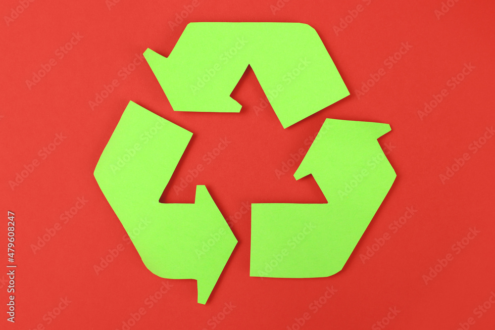 Icon of recycling made of green paper on a red background, the concept of protection, preservation of the environment Icon of recycling made of green paper on a red background, the concept of protection, preservation of the environment
